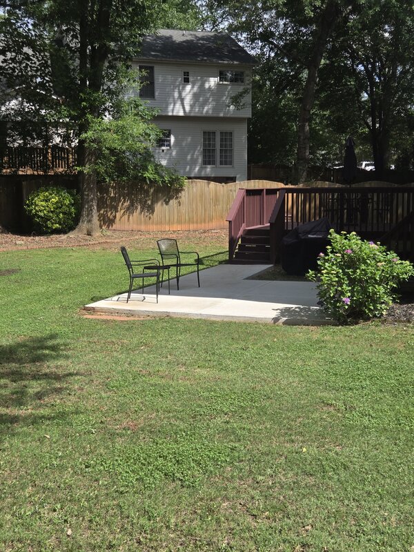 Maintained backyard with patio, deck, and flowering shrubs after routine lawn care
