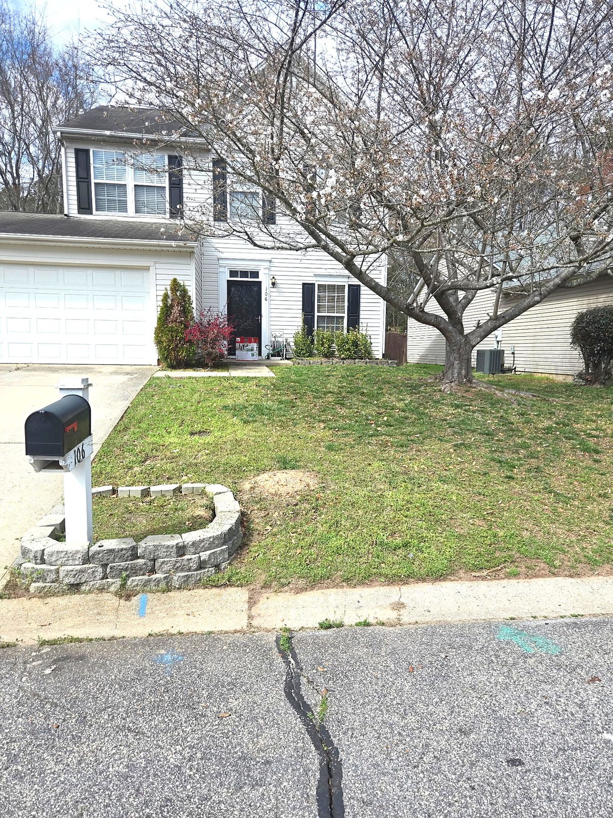 Front yard with stone wall and mailbox before lawn care